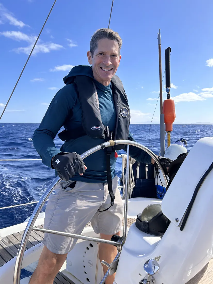 Robert at the helm of a sailboat on open water