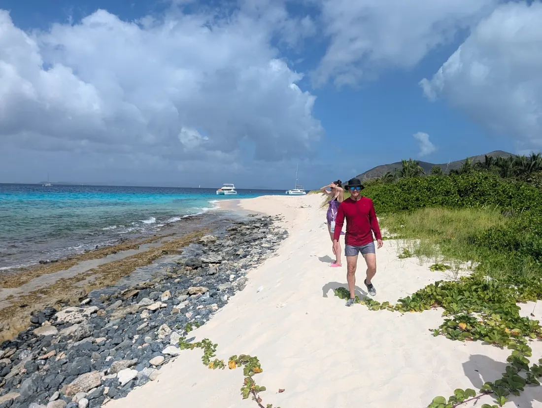 Walking a sand spit between turquoise water and green hills