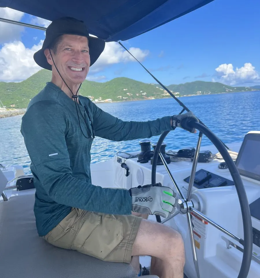 Robert at the helm of a catamaran, smiling