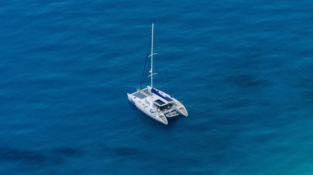 Catamaran under way on open blue water, from above