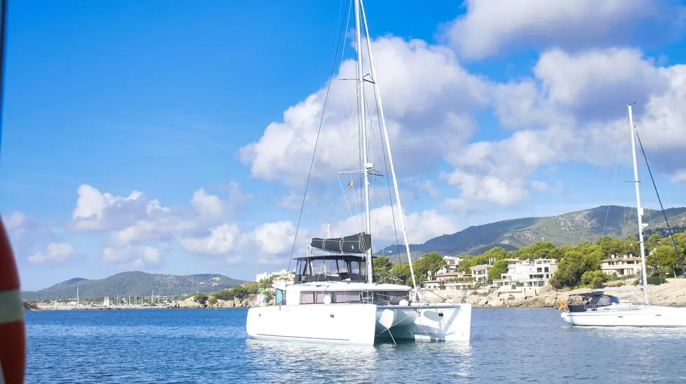 Catamaran at anchor off a Mediterranean village