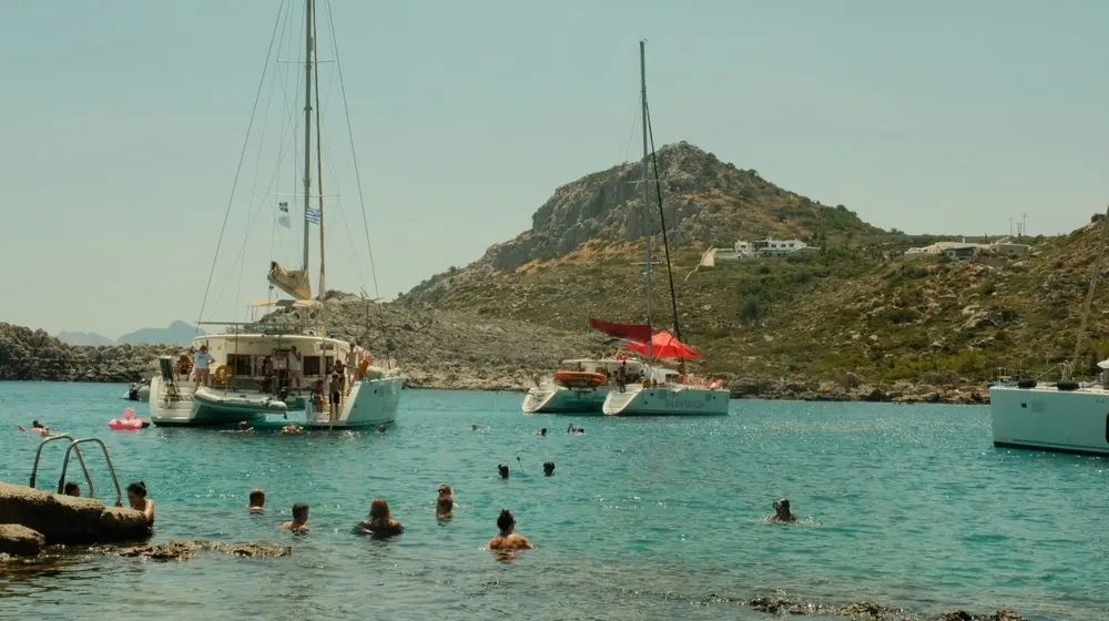 Friends swimming off two boats anchored in a turquoise cove